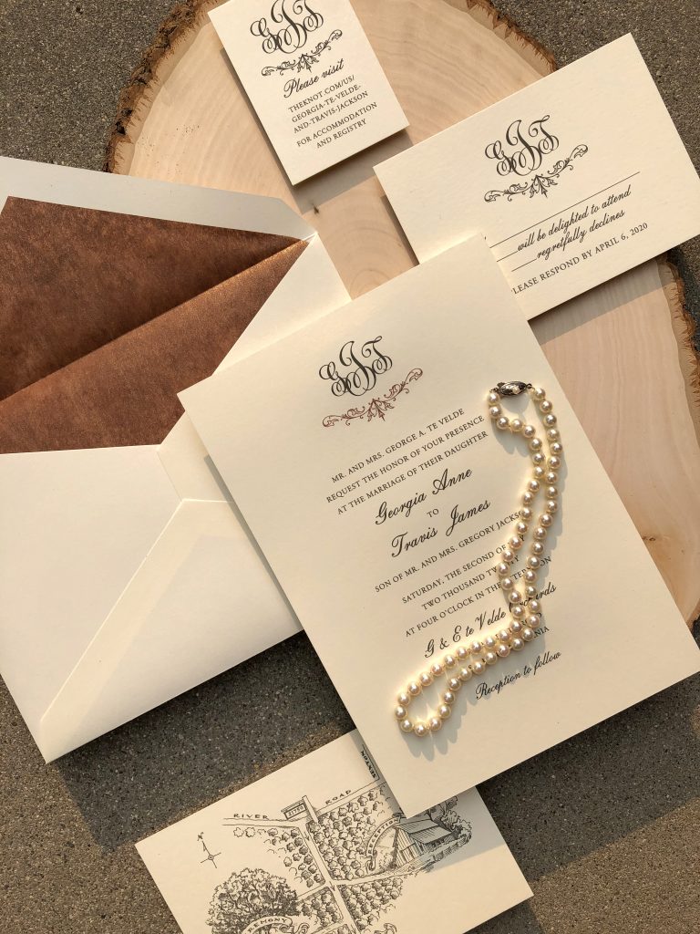 Custom invitations shown with engraved text and a monogram and copper liner